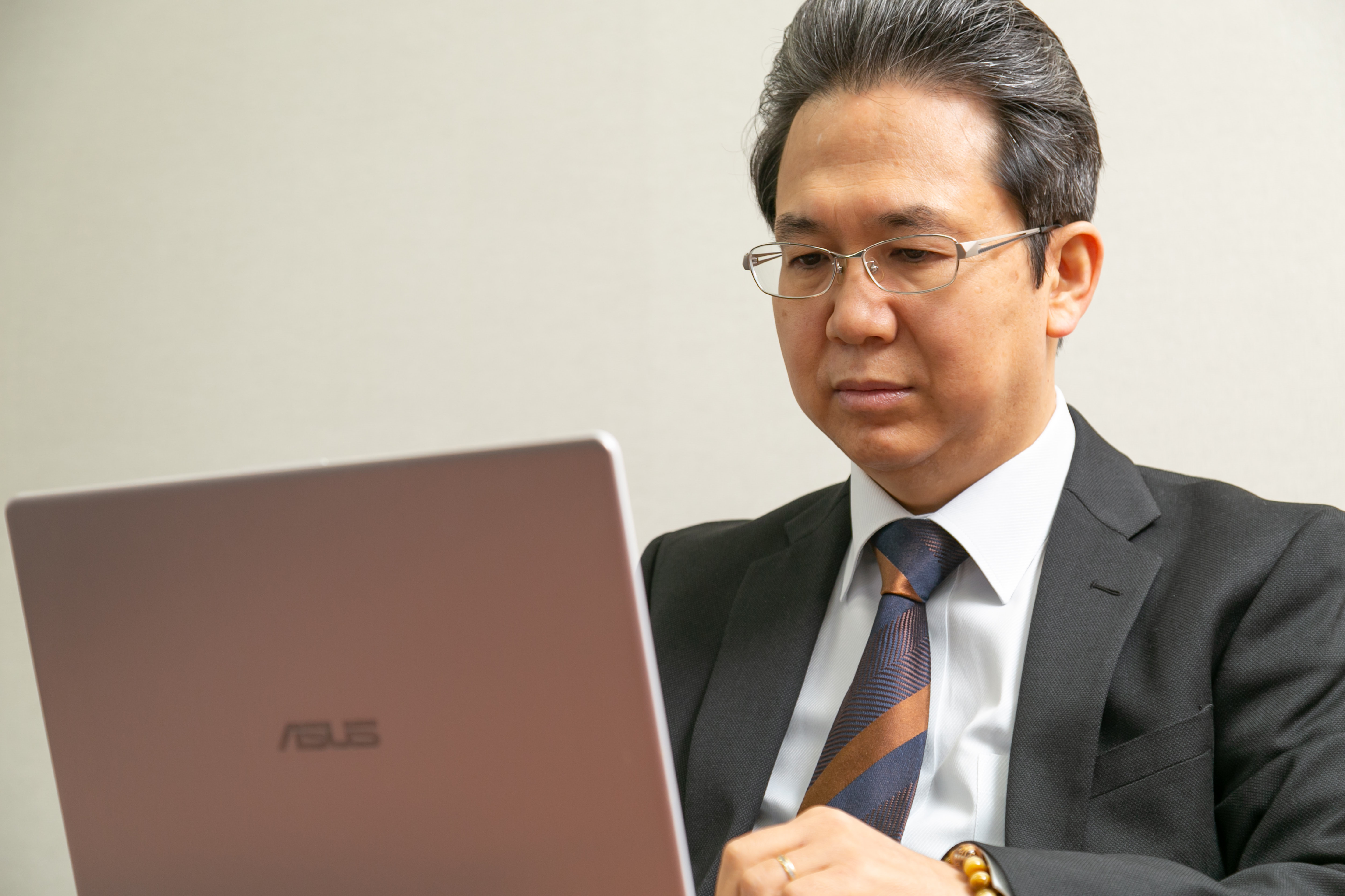 ノートパソコンの画面を真剣な表情で確認する、株式会社マネジメントオフィス・K代表取締役・川原一紀